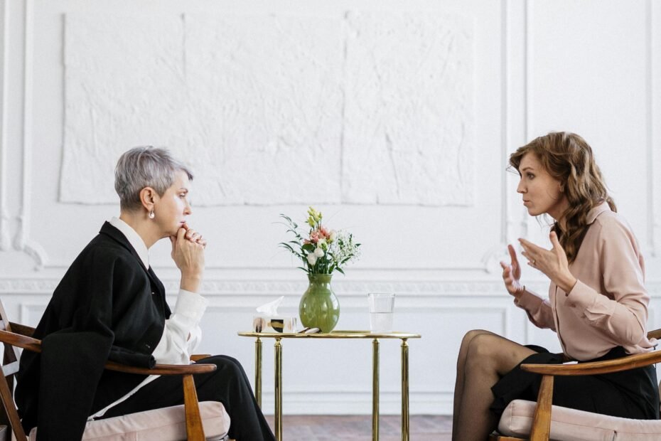 Two women engaged in a counseling session in a bright, modern loft setting.