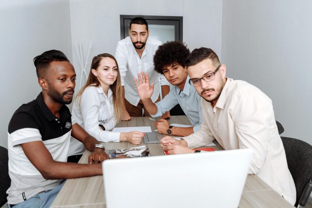 Diverse team collaborating around a laptop in a modern office. Multi-ethnic group engaged in a team meeting.